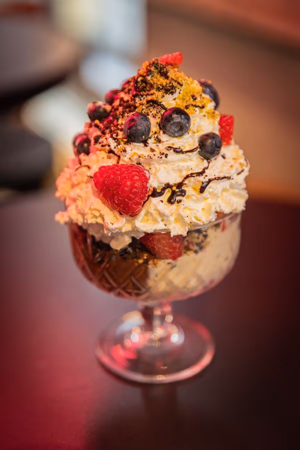Eiskaffee im Glas mit Sahne, Beeren und Schokosauce