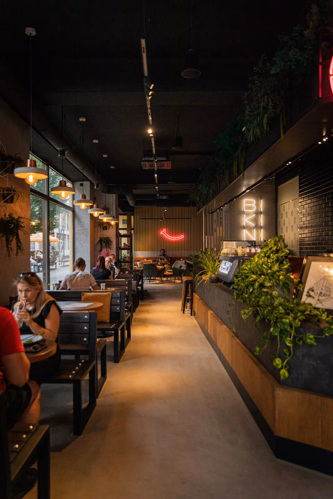 Blick durch das Café mit Theke, Pflanzen und Neon